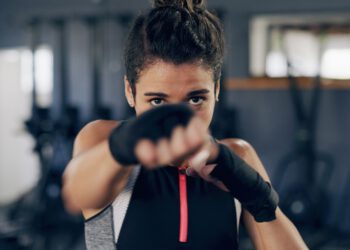 Woman, portrait and punch for martial arts at gym, training and confidence with power for fight. Person, athlete and fist with combat sports, exercise and workout at fitness club in Costa Rica.